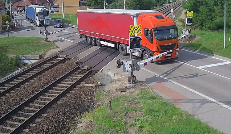 VIDEO: Řidič kamionu ignoroval červenou na přejezdu, kvůli vlaku pak prorazil závory