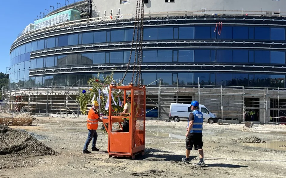 FOTO: Dělníci dokončili hrubou stavbu Areny Brno. Střechu zdobí májka pro štěstí